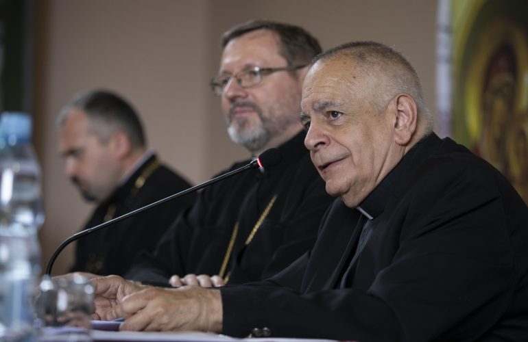 Msgr. Robert J. Vitillo speaking seated before a microphone