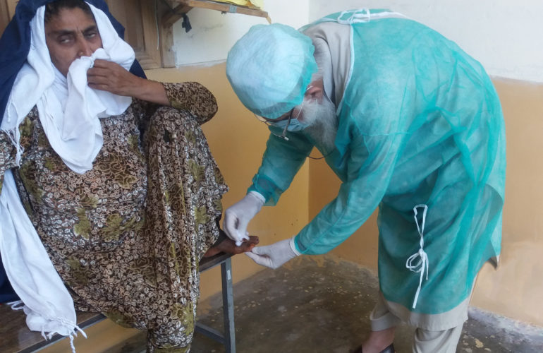 A health worker in Pakistan treats an Afghan woman with an injured toe