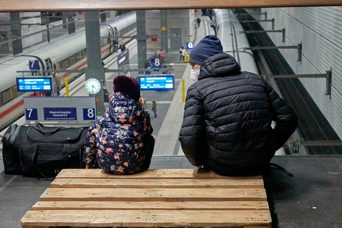 man and a boy sitting on stairs at train station with COVID masks