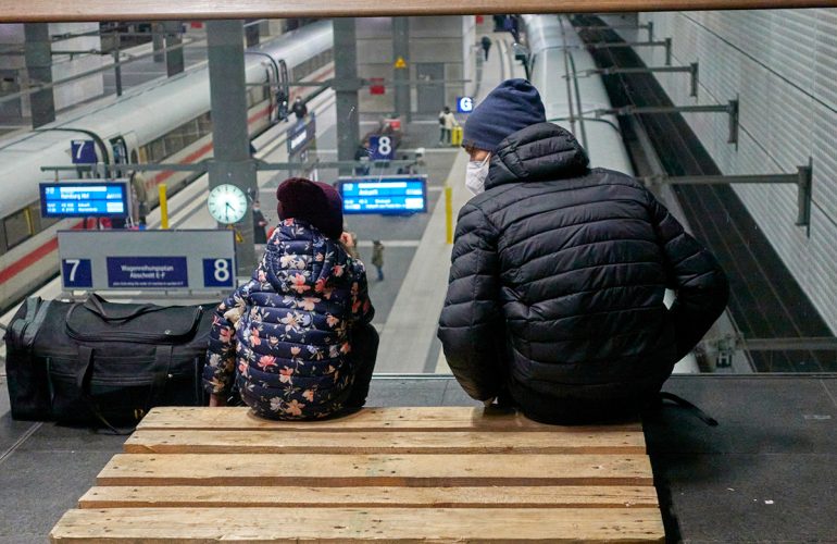 man and a boy sitting on stairs at train station with COVID masks