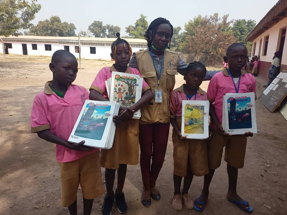 Children displaced by conflict and instability in the Central African Republic pose with their teacher and schoolbooks at school