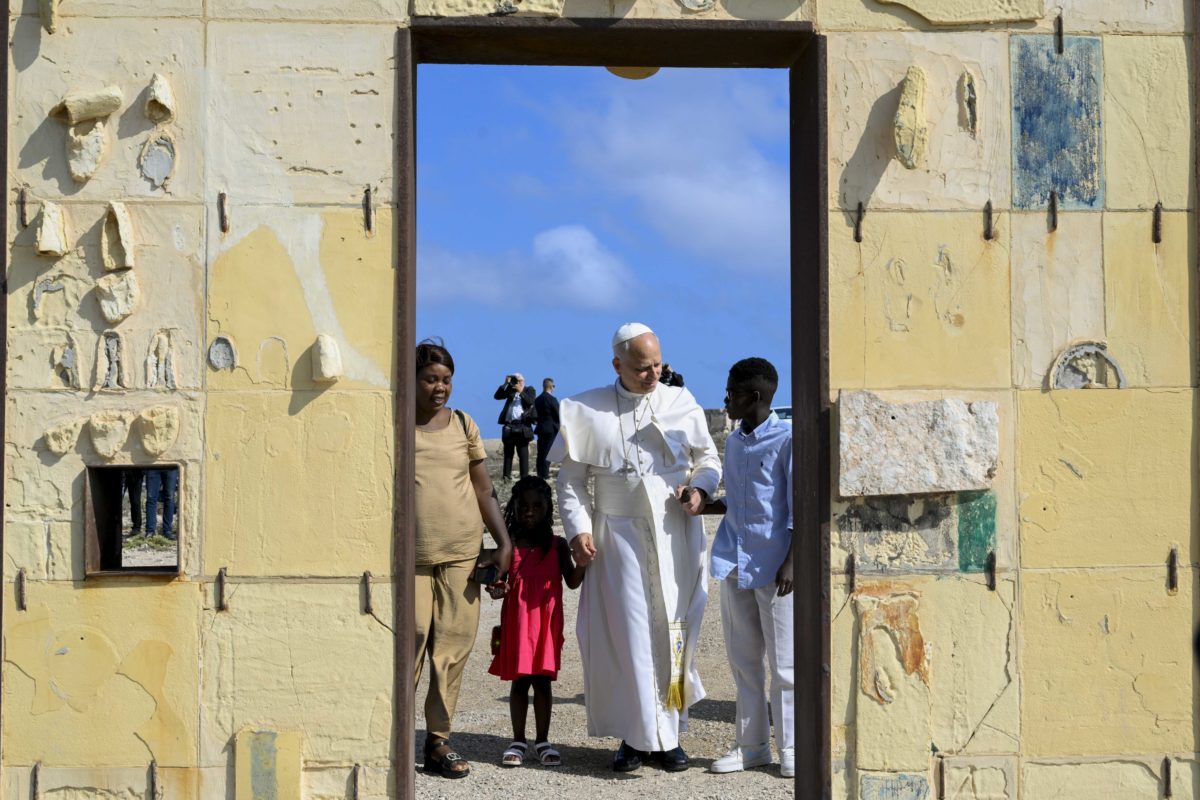 Pope Leo XIV and a migrant family at the 'Gateway to Europe' sculpture on the Italian island of Lampedusa, dedicated to migrants lost at sea while attempting to reach Europe. Taken during the Apostolic Visit to Lampedusa on 4 July 2026.